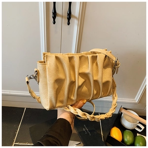 Close-up of cream pleated cloud bag with woven handle and thin shoulder strap