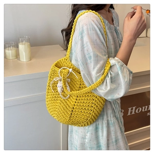 Detail of yellow hand-knitted tote bag with pearl charm and white rabbit doll accessory