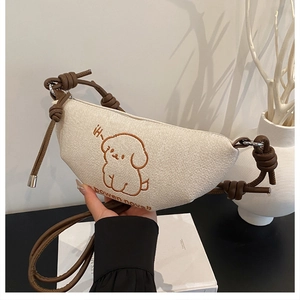Détail de la broderie chiot sur sac croissant en toile beige avec bandoulière nouée