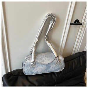 Dettaglio borsa a bauletto in denim blu con profili argento e ampia tracolla metallica