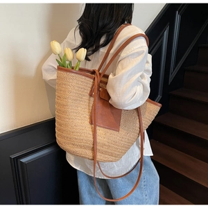 Detailed texture of large straw woven tote bag with brown leather trim and tulip decor