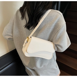Detail of white lychee leather texture on a chic saddle bag with gold metal buckle