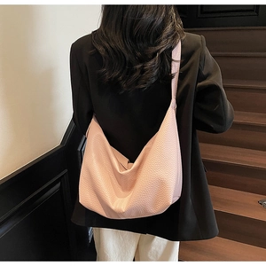 Close-up of pink minimalist dumpling bag showing grainy texture and wide shoulder strap