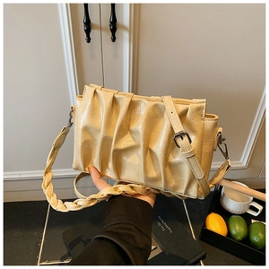 Detail of creamy yellow pleated shoulder bag with woven strap and vintage metal hardware