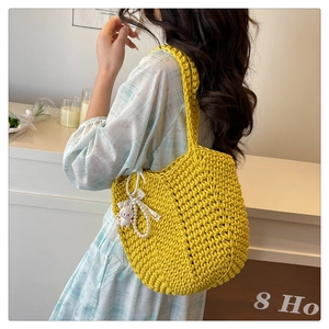 Detail of yellow knit tote bag featuring pearl charms and a plush bunny accessory
