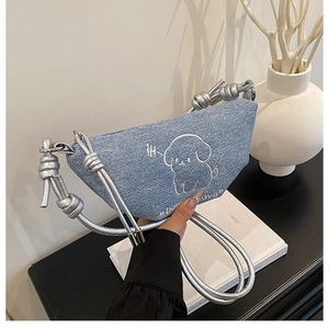 Détail du sac bandoulière en denim bleu avec broderie chiot et bandoulière argentée