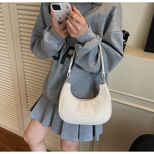 Close-up of white lychee leather dumpling bag with silver zipper and adjustable strap