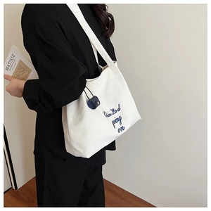 Détail du sac cabas en toile blanche avec broderie bleu marine et petit accessoire de pochette