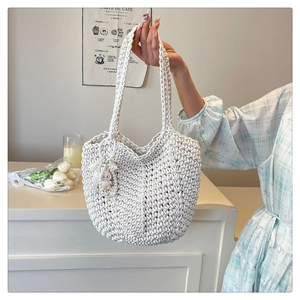 White hand-woven crochet tote bag with a purple bunny charm on a long shoulder strap