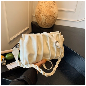 Detail of white pleated cloud bag with braided handle and adjustable leather crossbody strap