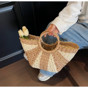 Detail of hand-woven straw tote bag with contrast stripes and metallic gold thread edge