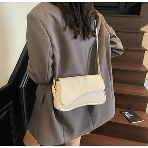 Détail du sac bandoulière en cuir verni crème avec sangle et boucle dorée