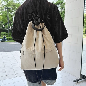 Outdoor-Aufnahme des cremefarbenen Nylon-Rucksacks mit Kordelzug und Stauraumansicht