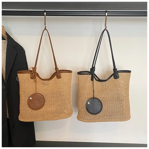 Detailed close-up of woven straw tote bags with leather trim and hanging mini pouches
