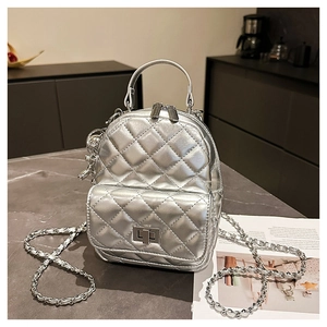 Detail of silver quilted mini backpack with metallic chain strap and bear charm
