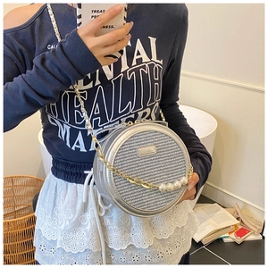 Detail shot of silver woven round bag with gold chain and large pearl accents