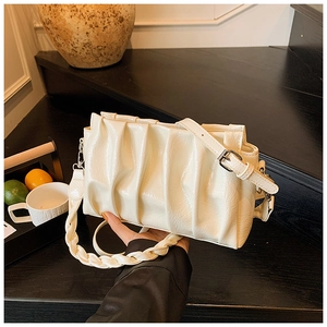 Detail of cream pleated cloud bag with woven handle and glossy PU leather finish