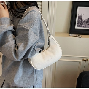 Detailed view of white hobo bag with lychee texture leather and silver zipper on shoulder