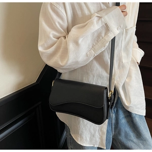 Detail view of black lychee grain leather crossbody bag with elegant gold metal hardware buckle