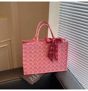 Close-up of pink jacquard tote bag with red Xi characters and a silk bow ribbon
