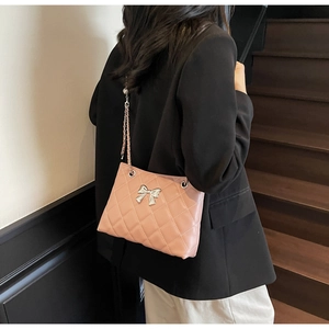 Side view of pink quilted leather crossbody bag with silver bow and chain strap on model