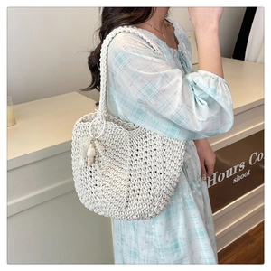 Close-up of woven shoulder bag with a cute white plush bunny charm on a summer dress