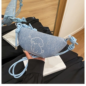 Détail du sac demi-lune en denim bleu clair avec broderie chiot et bandoulière corde