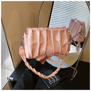 Detail of light pink pleated cloud bag featuring woven shoulder strap and glossy texture