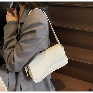 Sac sous le bras chic blanc crème avec détails dorés porté par un mannequin en ville