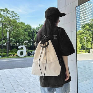 Details eines beige Kordelzug-Rucksacks aus Nylon mit verstellbaren Riemen und leichter Textur