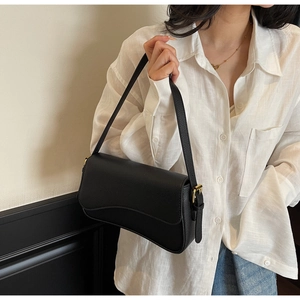 Detail of black lychee grain leather underarm bag with asymmetric flap and adjustable strap