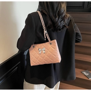 Detail of quilted leather crossbody bag with silver bow and adjustable chain strap