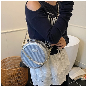 Detail of silver round crossbody bag featuring blue woven texture and pearl chain