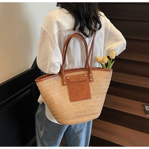 Macro shot of woven straw tote bag with brown leather pocket and dual handles detail