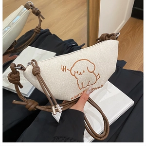 Détail du sac croissant beige avec chiot brodé marron et bandoulière en cuir nouée