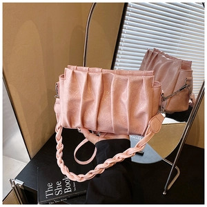 Detail of pink pleated cloud bag with shiny leather texture and woven handle design