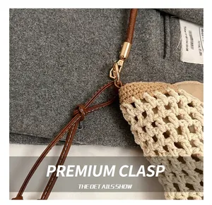 Detailed close-up of woven tote bag with premium golden metal hook and leather strap