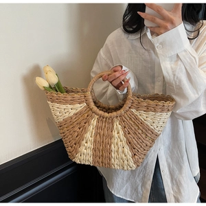 Detail of striped straw tote bag featuring beige weave with subtle gold metallic thread