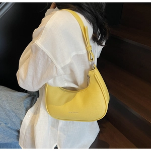 Close-up of bright yellow hobo bag with litchi texture worn with a white linen shirt