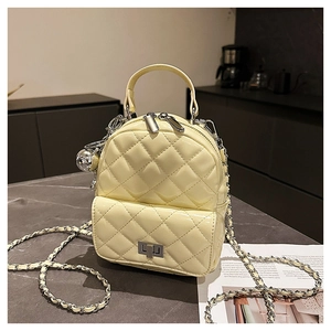 Close-up of quilted yellow patent leather backpack with silver chain and metal ball charm