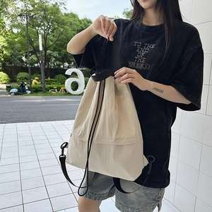 Detail der cremefarbenen Kordelzug-Tasche mit Nylon-Stoff und Metallschnallen