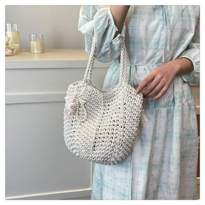 Detailed texture of white hand-woven tote bag with cute pendant in a home setting