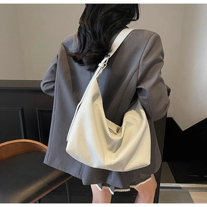 Detailed back view of a white pebbled leather hobo bag worn with a gray blazer