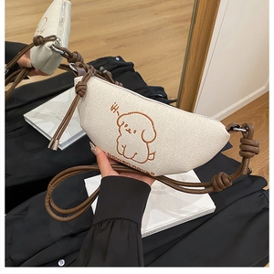 Détail de la broderie chiot sur sac demi-lune en toile crème avec bandoulière corde