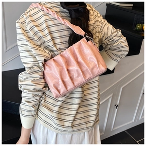 Detail of pink pleated cloud bag featuring glossy PU texture and woven shoulder strap