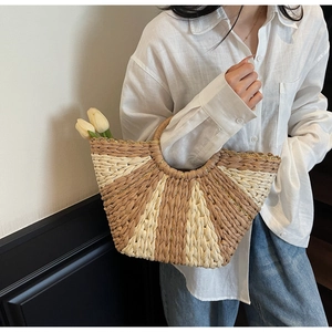 Detail of hand-woven straw handbag featuring chic semicircular shape and stripe pattern