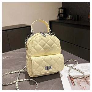Detail of cream yellow quilted backpack with silver clasp and chain on stone surface