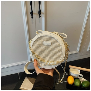 Detail of embroidered round straw bag with white faux pearls and a bow decoration
