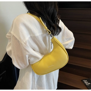 Detail of yellow pebbled leather crescent hobo bag worn with white linen shirt