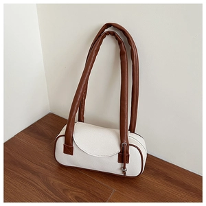 Dettaglio borsa in tela crema con finiture in pelle marrone e manico imbottito spesso
